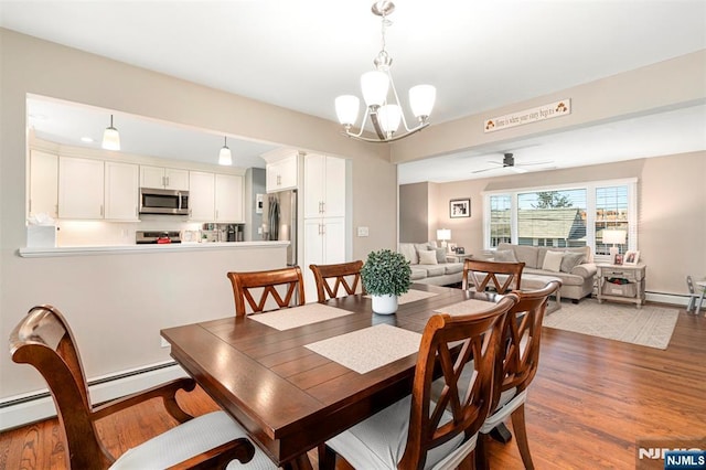 dining area featuring ceiling fan with notable chandelier, a baseboard radiator, and dark wood finished floors