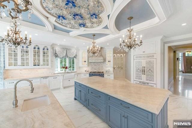 16 Shinnecock Trl, Franklin Lakes, NJ 07417 - kitchen featuring an inviting chandelier, blue cabinets, marble finish floor, a sink, and white cabinets