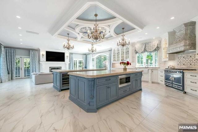 16 Shinnecock Trl, Franklin Lakes, NJ 07417 - kitchen featuring a notable chandelier, a kitchen island, tasteful backsplash, appliances with stainless steel finishes, and custom exhaust hood