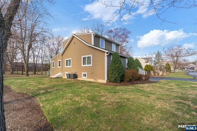 view of side of home featuring cooling unit and a lawn
