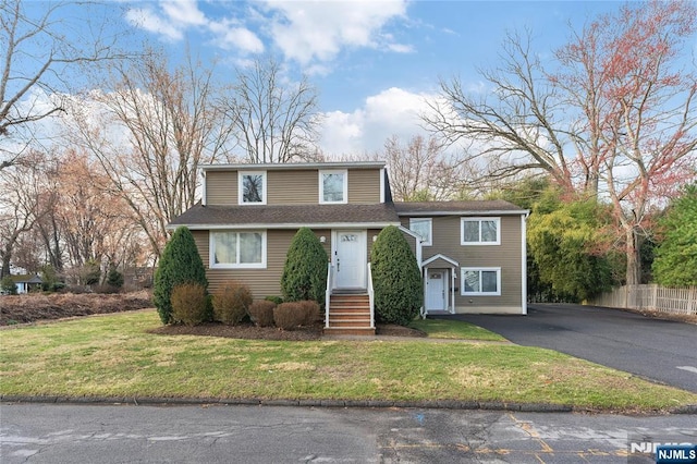 view of front facade featuring a shingled roof, driveway, and a front yard
