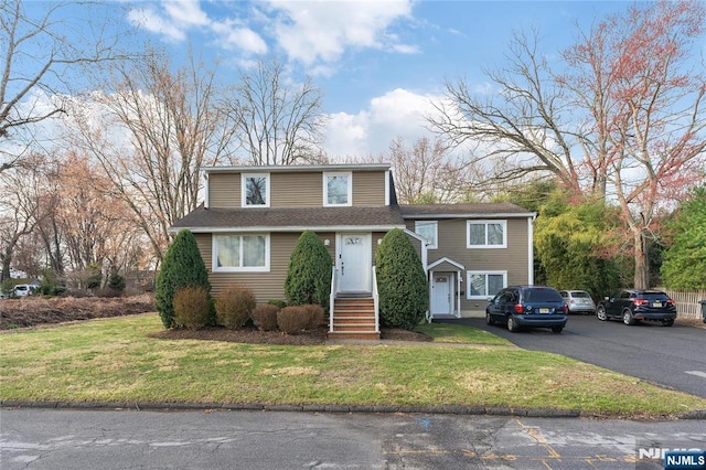 view of front of home with a front lawn and a shingled roof