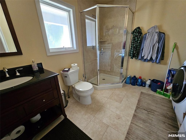 bathroom featuring toilet, tile patterned floors, vanity, and a stall shower