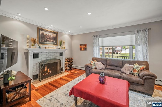 living area with crown molding, a brick fireplace, wood finished floors, a baseboard heating unit, and recessed lighting