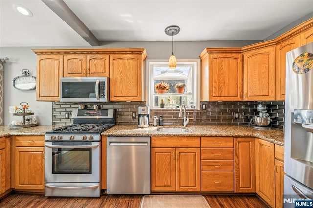 kitchen featuring light stone countertops, appliances with stainless steel finishes, a sink, and dark wood-type flooring