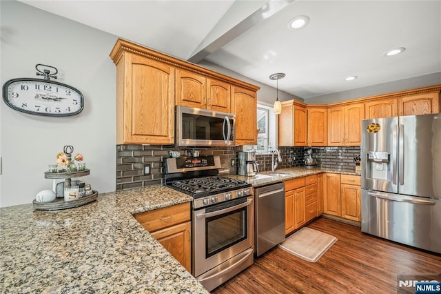 kitchen with pendant lighting, dark wood-type flooring, light stone counters, backsplash, and stainless steel appliances