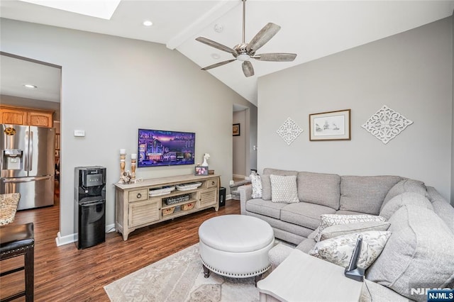 living area with vaulted ceiling with skylight, baseboards, a ceiling fan, and dark wood-type flooring
