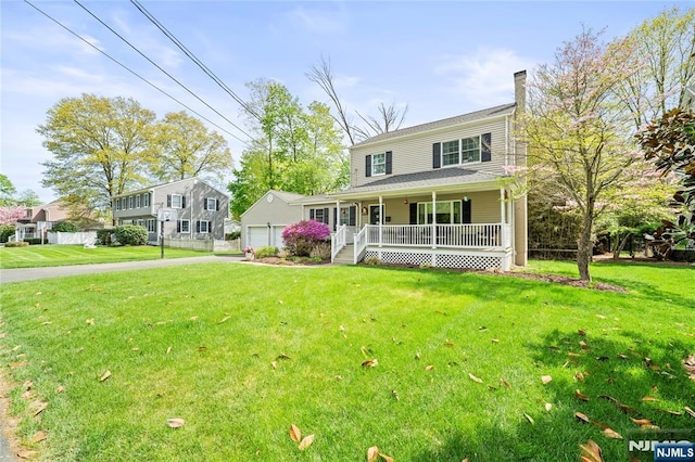 view of front of property featuring a garage, covered porch, and a front yard
