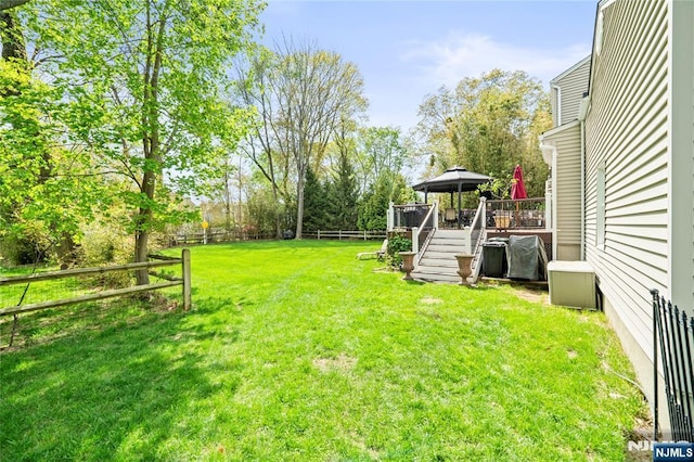 view of yard with a fenced backyard, a wooden deck, and stairway