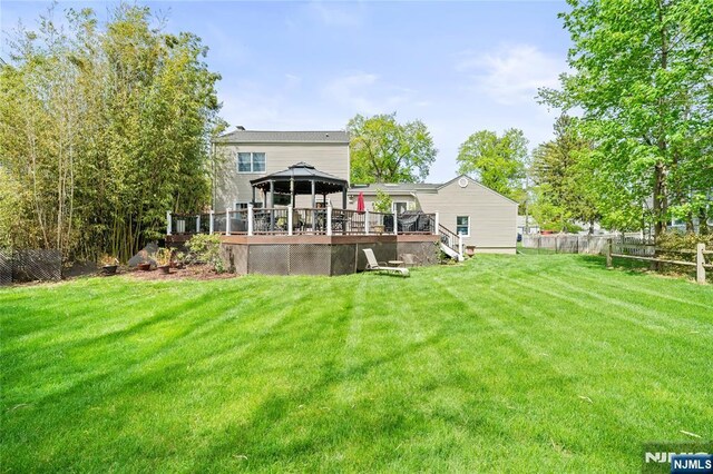 back of house featuring fence, a gazebo, a yard, and a deck