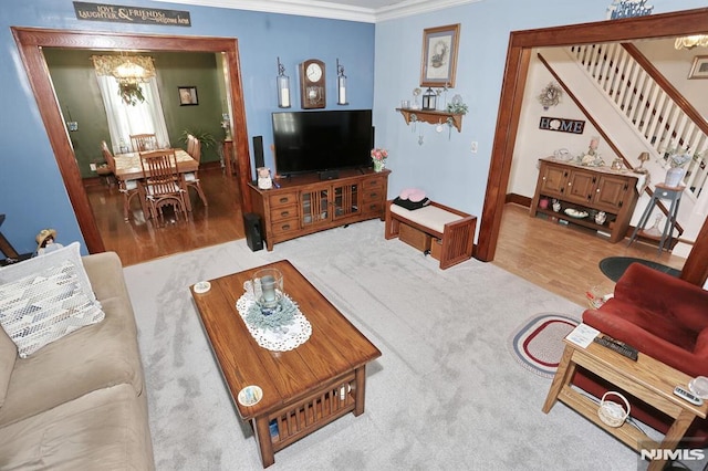 living room with wood finished floors, ornamental molding, stairs, and a notable chandelier