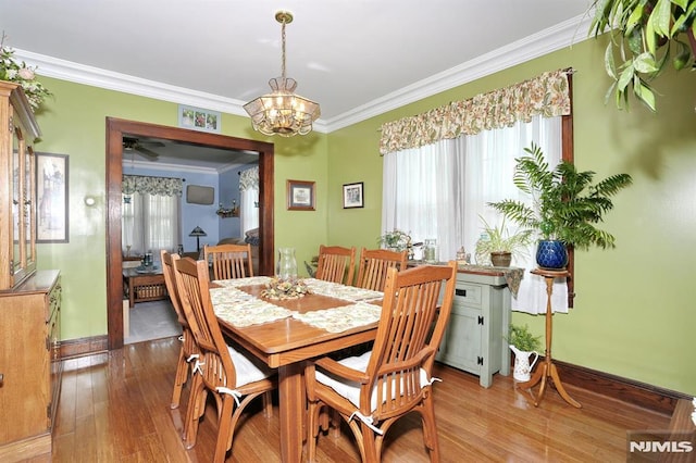 dining space with ceiling fan with notable chandelier, light wood-style flooring, baseboards, and ornamental molding