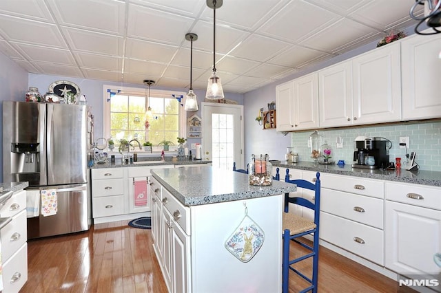 kitchen with a center island, wood finished floors, a sink, and stainless steel fridge