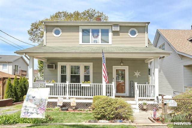 view of front of home with a porch and a wall unit AC