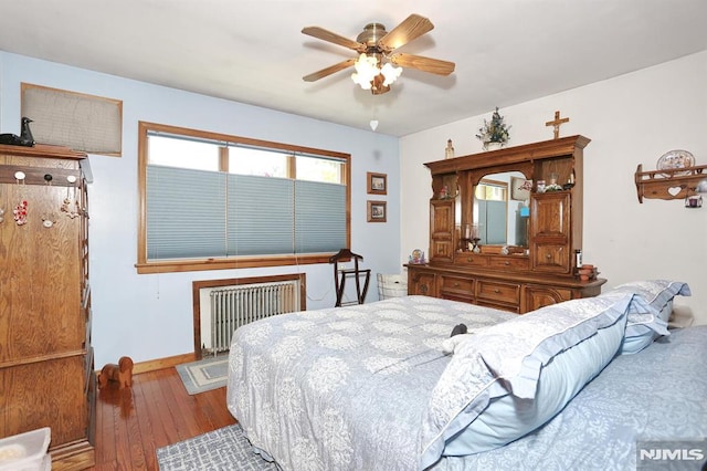 bedroom featuring radiator heating unit, hardwood / wood-style floors, a ceiling fan, and baseboards