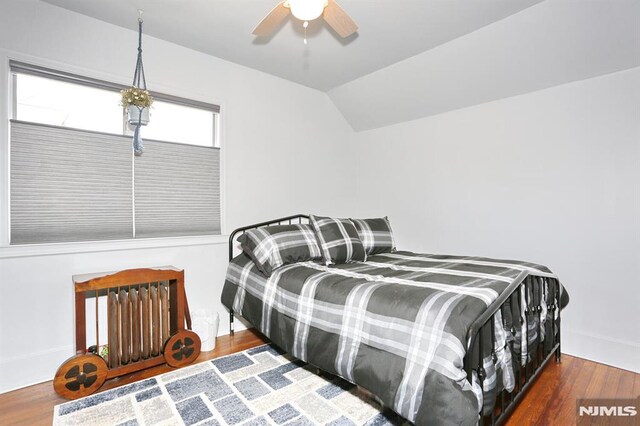 bedroom featuring wood finished floors, lofted ceiling, baseboards, and ceiling fan