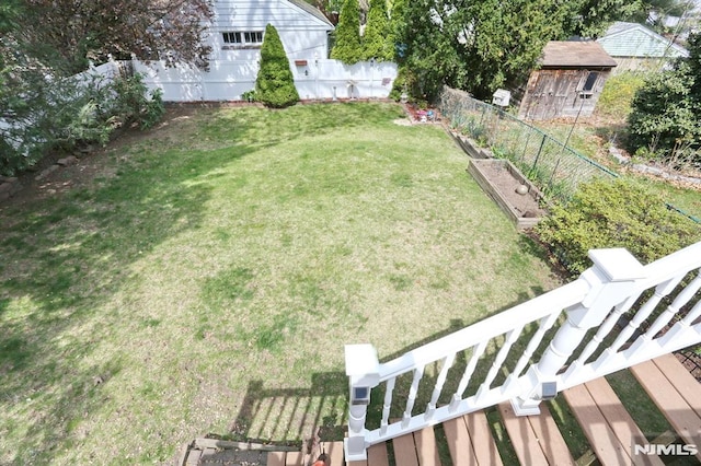 view of yard with fence, a garden, and an outdoor structure
