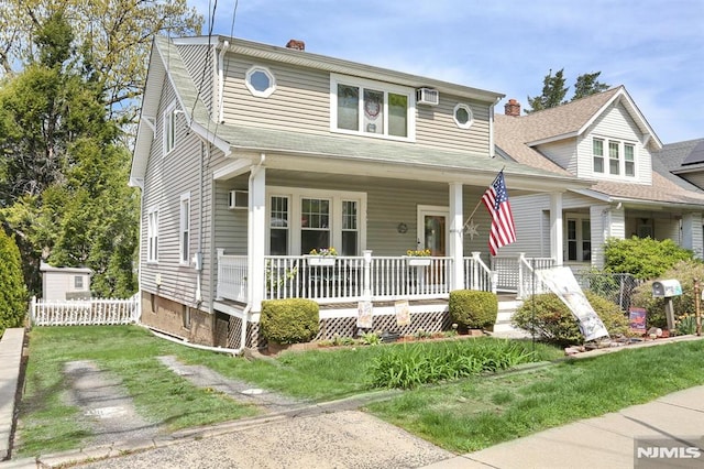 view of front facade featuring an AC wall unit, a chimney, fence, a porch, and a front yard