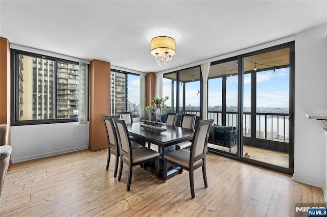 dining space featuring baseboards, a wealth of natural light, an inviting chandelier, and light wood-type flooring