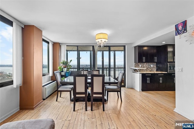 dining area with radiator heating unit, light wood-style flooring, baseboards, and a chandelier