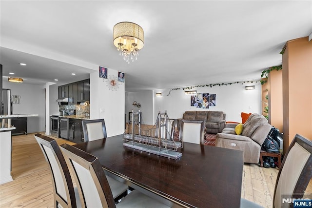 dining space featuring light wood-style flooring, recessed lighting, and a notable chandelier