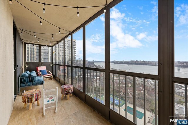 sunroom / solarium featuring floor to ceiling windows, track lighting, a water view, and a city view