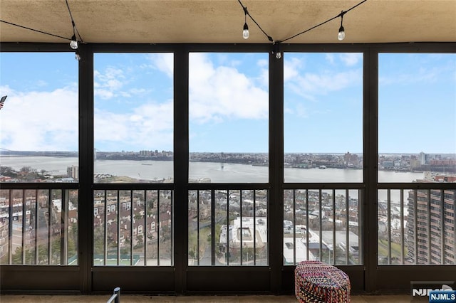unfurnished sunroom with a water view, a view of city, and plenty of natural light