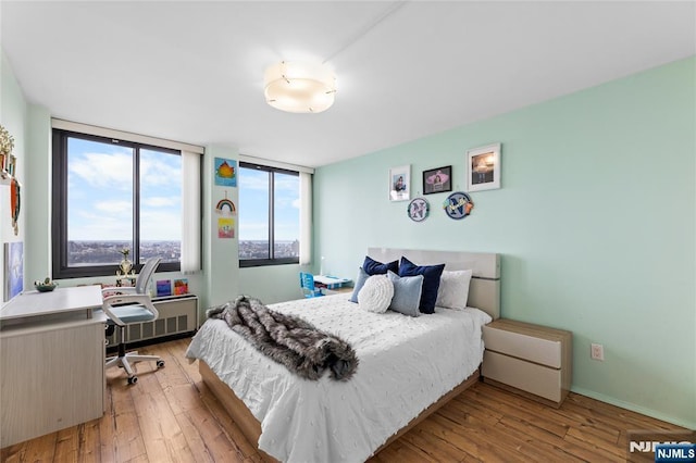 bedroom with radiator, hardwood / wood-style flooring, and baseboards
