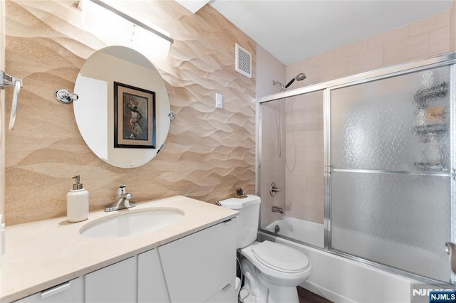 bathroom with visible vents, toilet, bath / shower combo with glass door, and vanity
