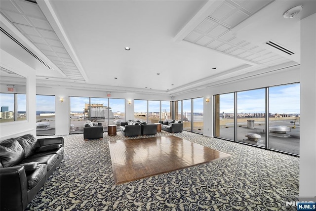 living area with carpet flooring, a tray ceiling, visible vents, and a healthy amount of sunlight