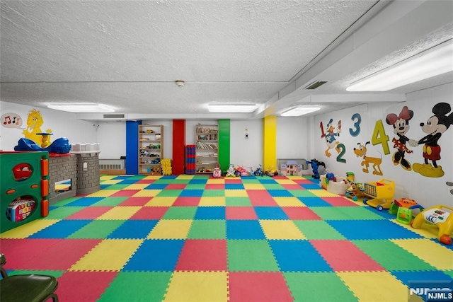 recreation room featuring visible vents and a textured ceiling