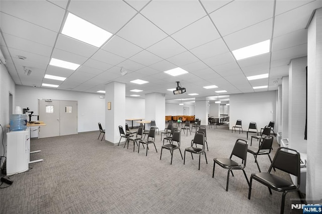 carpeted dining space with a paneled ceiling