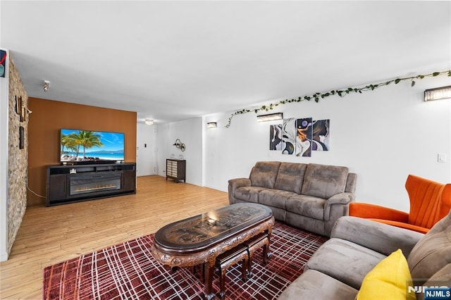 living room featuring a glass covered fireplace and wood finished floors