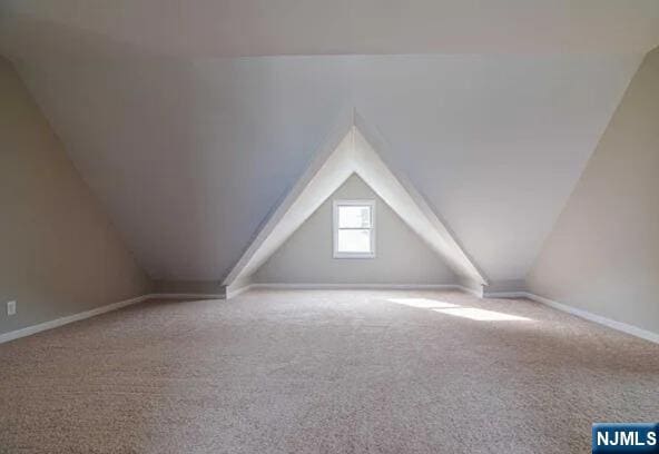 additional living space with baseboards, carpet flooring, and vaulted ceiling