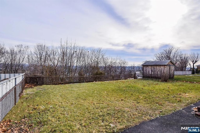 view of yard featuring an outbuilding, a storage unit, and a fenced backyard