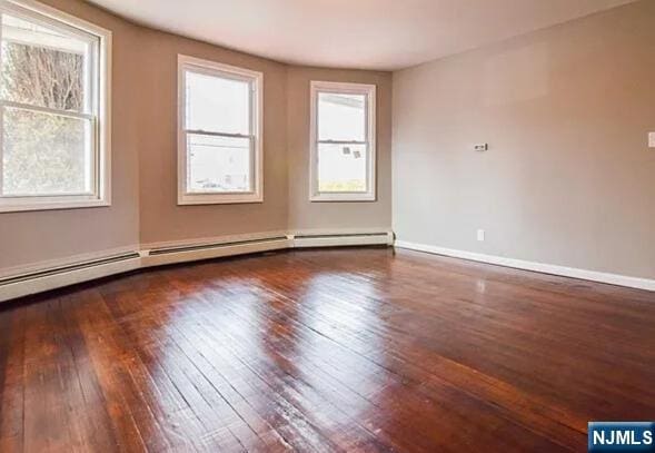 unfurnished room featuring hardwood / wood-style flooring, baseboards, and a baseboard radiator