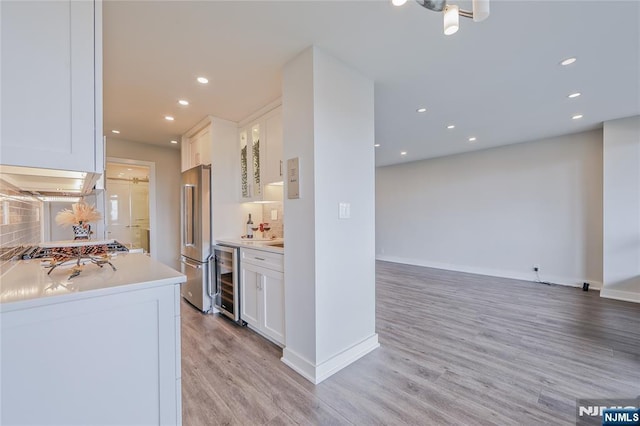 2077 Center Ave Unit 11C, Fort Lee, NJ 07024 - kitchen featuring appliances with stainless steel finishes, wine cooler, light wood finished floors, white cabinetry, and light countertops
