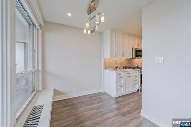 2077 Center Ave Unit 11C, Fort Lee, NJ 07024 - kitchen with appliances with stainless steel finishes, tasteful backsplash, light wood-type flooring, light countertops, and white cabinetry