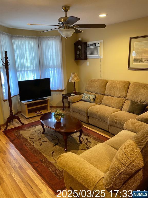 living room with a ceiling fan, recessed lighting, a wall mounted air conditioner, and wood finished floors