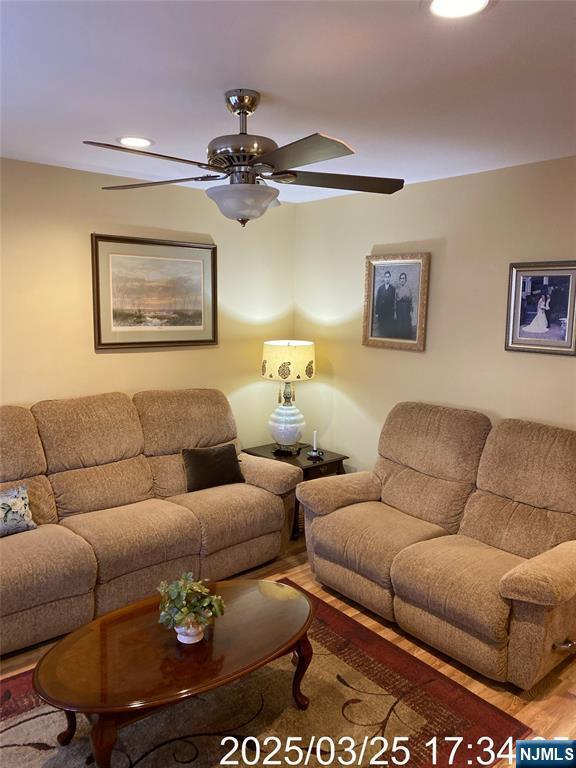 living room with wood finished floors and a ceiling fan