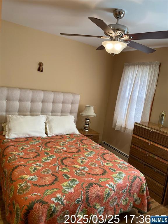 bedroom with a baseboard heating unit and ceiling fan