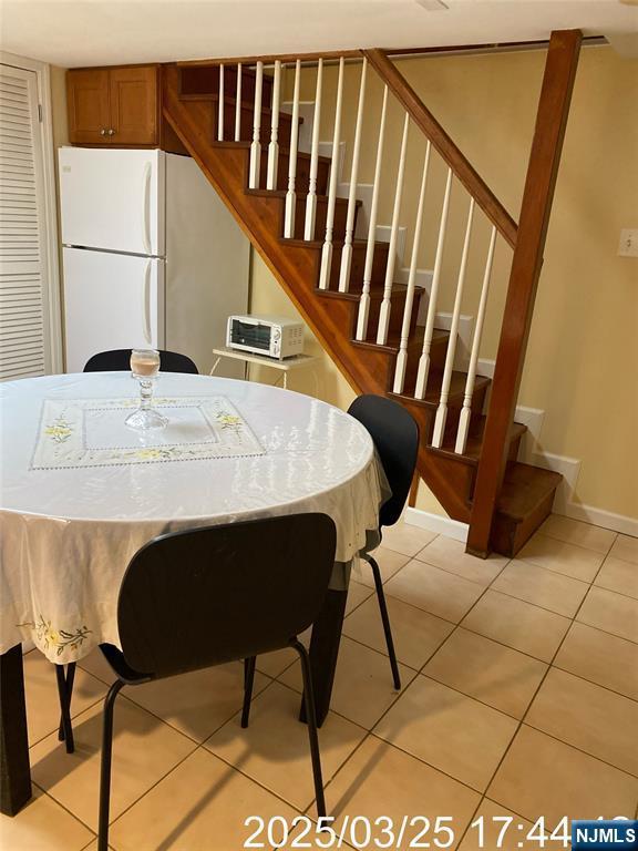 dining room with light tile patterned floors, baseboards, and stairs