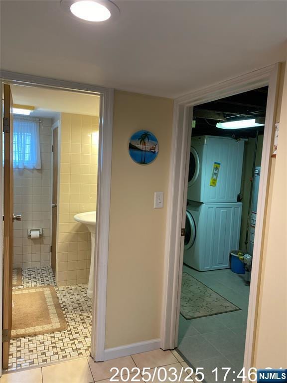 bathroom featuring stacked washer / dryer, tile patterned floors, and a stall shower