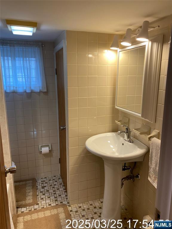 bathroom with tile patterned flooring and tile walls