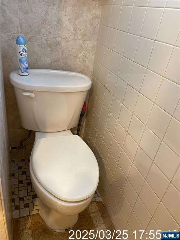 bathroom with tile walls and toilet