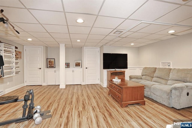 living area featuring wood finished floors, a paneled ceiling, a decorative wall, and recessed lighting