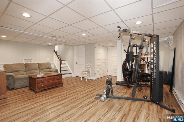 workout area featuring wood finished floors, a drop ceiling, and recessed lighting