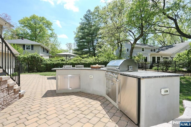 view of patio / terrace with exterior kitchen, fence, and a grill