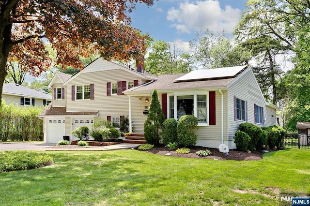 tri-level home featuring an attached garage, driveway, and solar panels