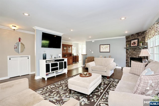 living room featuring ornamental molding, healthy amount of natural light, baseboards, dark wood-type flooring, and a stone fireplace